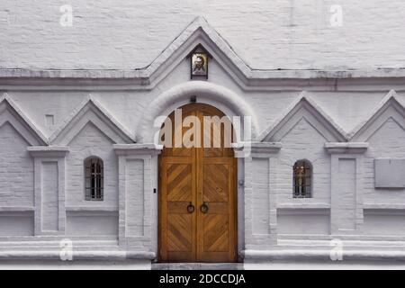 Wooden gate and two arched windows on a white brick wall. Entrance to the old christian church Stock Photo