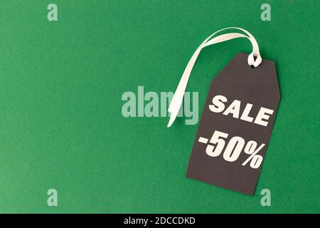 One black tag with text sale on a green background. Copy space for your text. Black Friday concept. Stock Photo