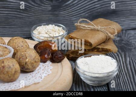 Dried fruit and oatmeal sweets. Nearby ingredients for their preparation. On black pine boards. Stock Photo