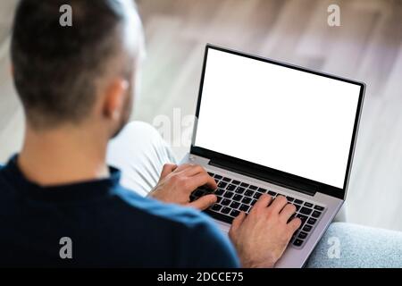 Guy Sitting On Sofa Using Laptop In Living Room Stock Photo