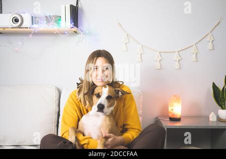 Portrait of a happy woman with her staffordshire terrier dog. Joy from pets at home or during lockdown or self isolation, cold winter season Stock Photo