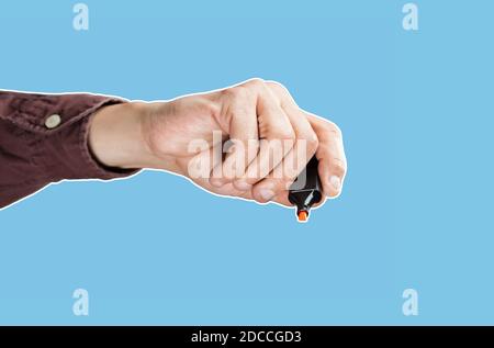 A man's hand holds an orange marker on a blue background. Magazine style collage with copy space. Abstract creative background Stock Photo