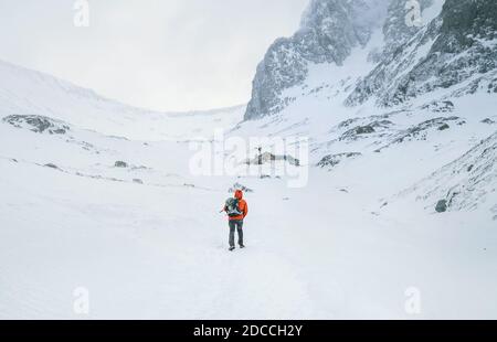 Alone mountaineer has a solo winter Ben Nevis 1345m summit approaching in high mountains on windy snowy weather at Highlands of Scotland. Stock Photo