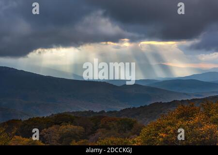 Atmospheric landscape with sun rays through clouds. Dramatic sky with bright sun rays over the autumn forest in the mountains. Crimean nature reserve Stock Photo