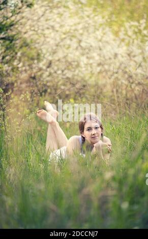 The girl lies on the grass in the spring forest Stock Photo
