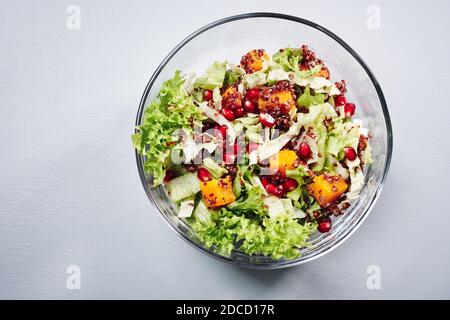 Salad with lettuce, pumpkin, red quinoa and pomegranate in a glass bowl. Stock Photo
