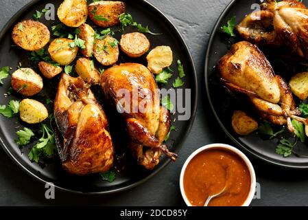 Close up of tasty grilled quails carcasses on black stone background. Top view, flat lay Stock Photo