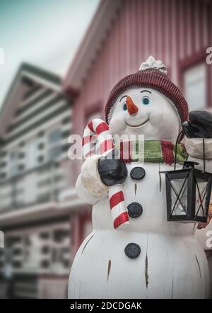 Funny snowman in christmas scene with colorful houses Stock Photo