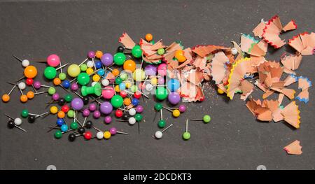 Black hard cover of a book as a background with colored pins and traces of colored pencils. Stock Photo