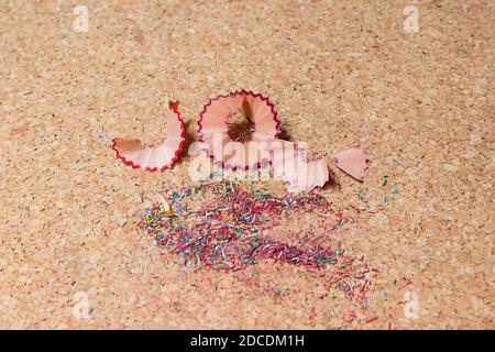 Colored pencil shavings and fine wood scraps with geometric shapes on a cork notice board. Stock Photo