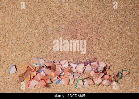 Colored pencil shavings in line on a corkboard. Horizontal image with copy space to enter your text. Stock Photo