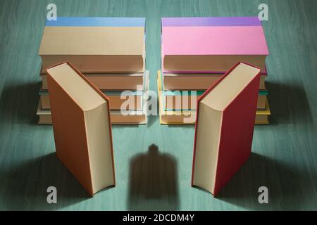 Composition of books of different sizes and colors with an intriguing shadow on a green wooden table. Creative reading. Stock Photo