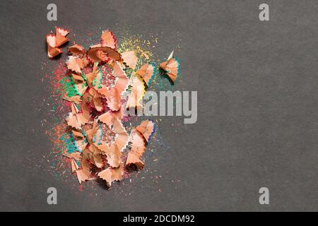 A pile of leftover colored wood of a sharpener pencil on a textured black background. Space to enter text. Stock Photo
