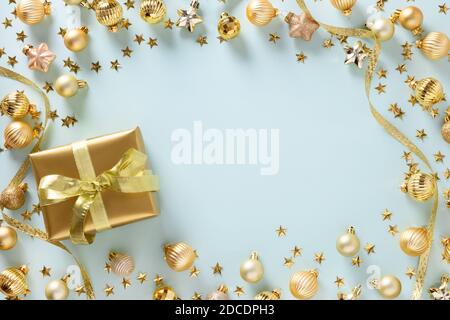 Christmas frame of golden gift and balls on blue. Top view. Xmas border for wishes. Holiday greeting card. Stock Photo