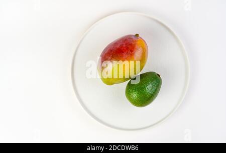 Fresh mango and avocado on a white plate on a light background. Stock Photo