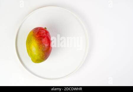 Juicy ripe mango on a white plate on a light background. Stock Photo
