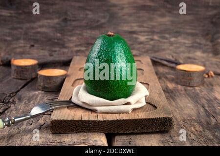 White plate with whole avocado and Cutlery on a light background. Stock Photo