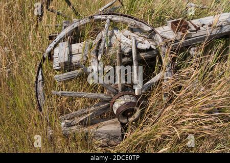 A broken-down old pioneer wagon with wooden-spoke wheels on a ranch in Idaho.  Now part of a private museum. Stock Photo