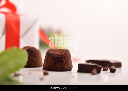 Christmas composition with chocolate truffles on white table with gift and Christmas decoration. Front view. Horizontal composition. Stock Photo