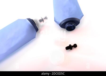 Blue plastic soft flasks, isolated on white background, must be cleaned to avoid bacteria proliferation by removing the cap. Stock Photo