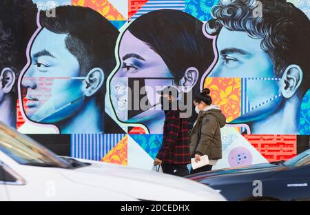 Toronto, Canada. 20th Nov, 2020. People wearing face masks walk past a mural in Toronto, Canada, on Nov. 20, 2020. Canadian Prime Minister Justin Trudeau said on Friday that the country is at stake as COVID-19 has been worsening. As of Friday afternoon, Canada reported a total of 319,038 cases and 11,313 deaths. Credit: Zou Zheng/Xinhua/Alamy Live News Stock Photo