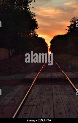 Burlington, Illinois, USA. Unoccupied railroad tracks stretch to a vanishing point on the horizon just before sunset. Stock Photo