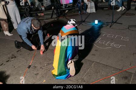 New York, United States. 20th Nov, 2020. People rally and hold vigil on transgender day of remembrance to commemorate lost lives on Washington Square. People remember lives of transgender victims of violence and celebrated lives of those who live. People were wearing mostly white dresses in memory of those who died. They put frames with portraits of victims and laid white flowers and lit candles. A woman seen writing message on the ground. (Photo by Lev Radin/Pacific Press) Credit: Pacific Press Media Production Corp. Stock Photo