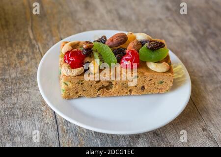 The top fruit cake from the white placed on the wooden table Stock Photo