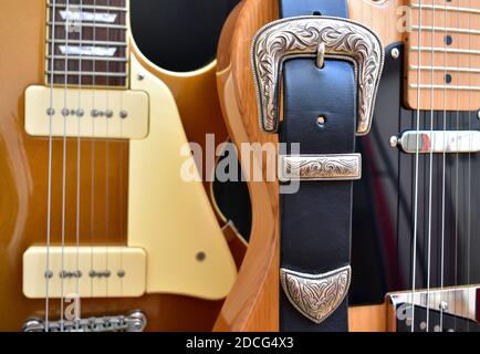 Electric guitars and leather strap with silver buckle close-up. Stock Photo