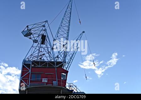 Abandoned old shipyard crane made from steel with blue skies backdrop. Stock Photo