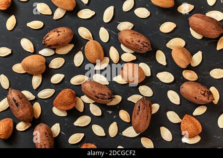 Whole almonds, pecan nuts and pumpkin seeds mixed on black marble like board, view from above Stock Photo