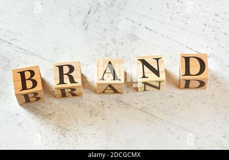 Five wooden cubes with word BRAND on white stone like board, view from above