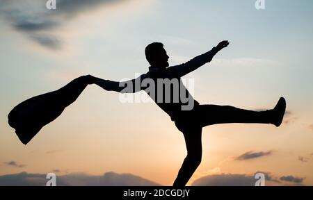dancing man silhouette with jacket against sunset sky, freedom. Stock Photo