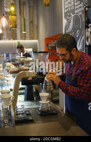 Germany/ Frankfurt Main /Coffee Style /Barista pouring water into drip filter to make filter coffee .Barista pouring coffee through filter in cafe. Stock Photo