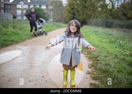 Happy little girl smiling adorably after jumping in a muddy puddle Stock Photo