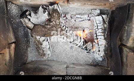 Small flames on firewood logs. Abstract background in shades of black and gray ash shades. Camping concept. Smoldering bonfire closeup Stock Photo