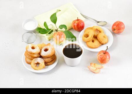 Apple rings on white plate, cup of black coffee on light stone background Stock Photo