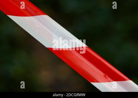 Red and white plastic warning barrier tape on dark background with copy space Stock Photo