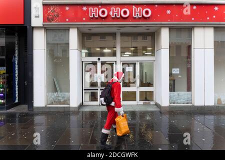 Glasgow, Scotland, UK. 21 November 2020. Views of Saturday afternoon in Glasgow city centre on first day of level 4 lockdown. Non essential shops and businesses have closed. And streets are very quiet. Pictured; Man dressed as Santa Claus walks in front of closed  down Christmas store called Ho Ho Ho   .Iain Masterton/Ģ����ý Live News Stock Photo
