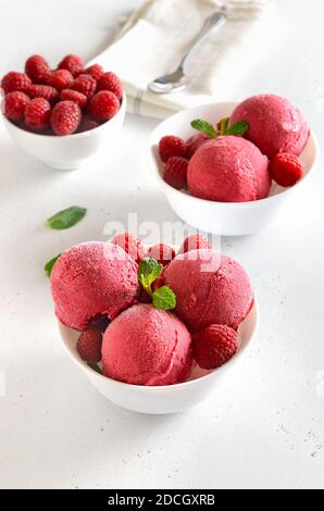 Homemade raspberry ice cream scoop with fresh raspberries in white bowl. Cold summer dessert Stock Photo