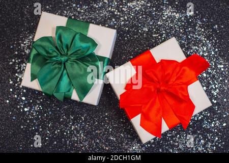 Christmas gift boxes or present with bow ribbon on magic silver glitter on black background. Stock Photo