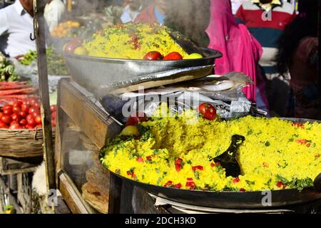 Indian traditional dish poha (Pohe) with vegetables and spices on the market. Vendor with breakfast street food morning, Pushkar, Rajastan, India Stock Photo