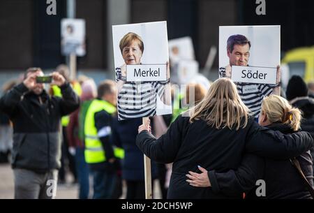 21 November 2020, Baden-Wuerttemberg, Göppingen: Chancellor Merkel (CDU) and Bavarian Prime Minister Söder (CSU) in 'prisoner clothing' can be seen on signs of two women during a demonstration against the Corona policy of the federal government. Photo: Christoph Schmidt/dpa Stock Photo