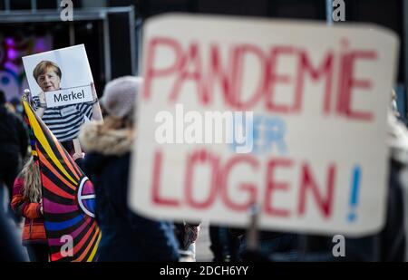 21 November 2020, Baden-Wuerttemberg, Göppingen: 'Pandemic of Lies!' is written on the sign of a participant in a demonstration against the Corona policy of the federal government. In the background is a sign depicting Chancellor Merkel in 'convict clothes'. Photo: Christoph Schmidt/dpa Stock Photo