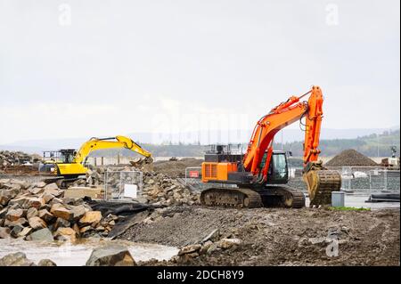 Construction site diggers yellow and orange during excavation Stock Photo