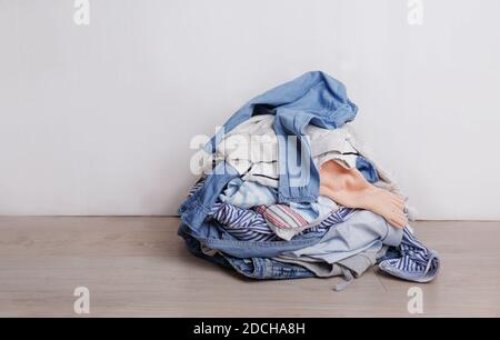 a pile of colorful clothes lying on the floor on a light background Stock Photo