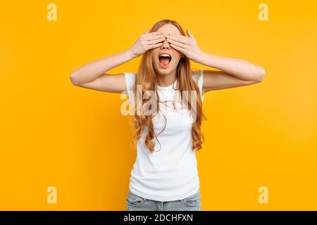 beautiful girl closes her eyes with her hands, on a yellow background Stock Photo