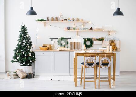 New year and Christmas. Festive Scandinavian cuisine in Christmas decorations. Candles, fir branches, wooden stands, table. Stock Photo