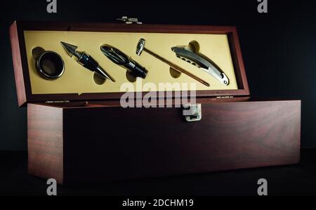 Luxury wooden wine box with five accessories piece gift set, includes the standard bottle stopper, corkscrew, pourer, drip ring and wine thermometer. Stock Photo