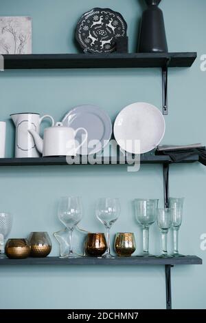 Kitchen utensils on the shelves: glass glasses, gold glasses, plates, teapots in the kitchen